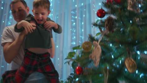Father-lifts-boy-to-dress-star-on-top-of-Christmas-tree.-High-quality-4k-footage